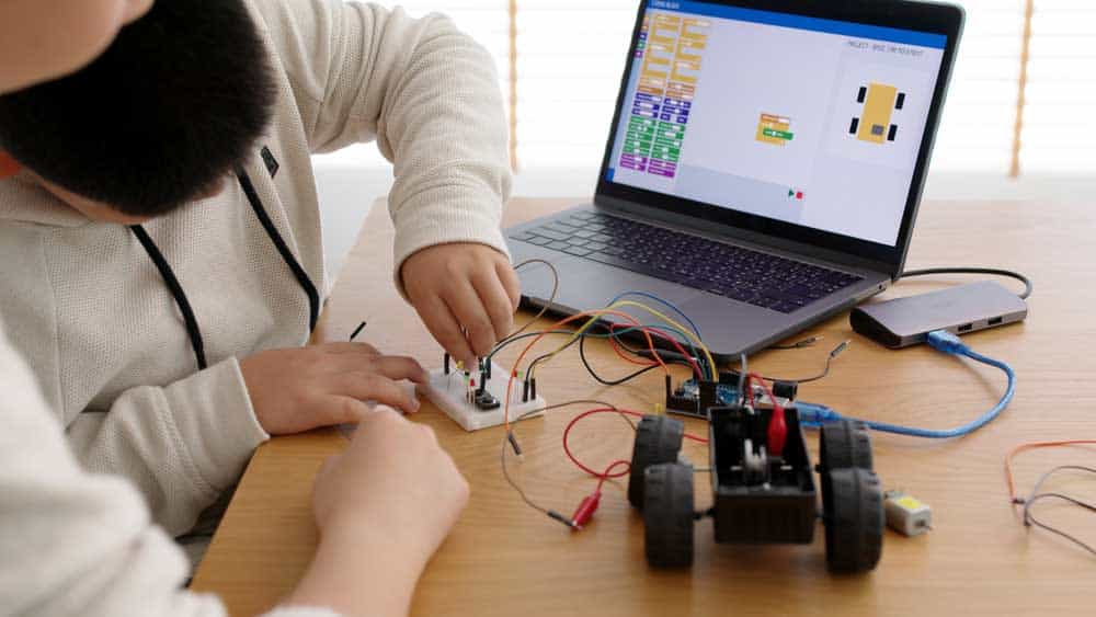 A young STEM student coding a robot car
