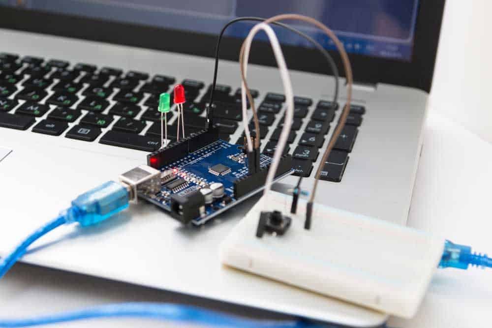 A microcontroller board connected to a computer via USB for programming