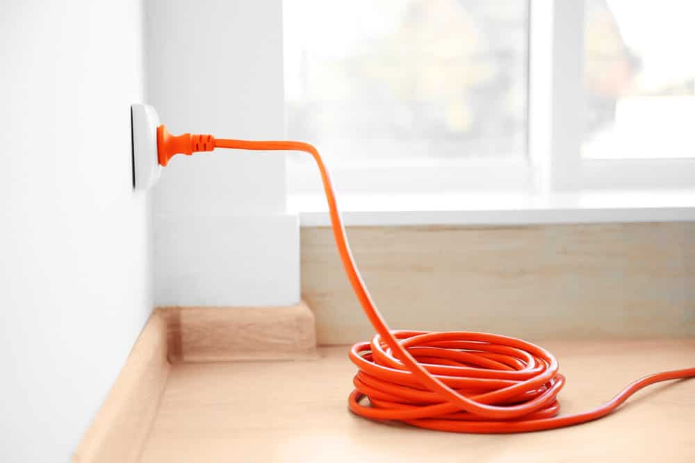 Orange extension into power outlet indoors. 