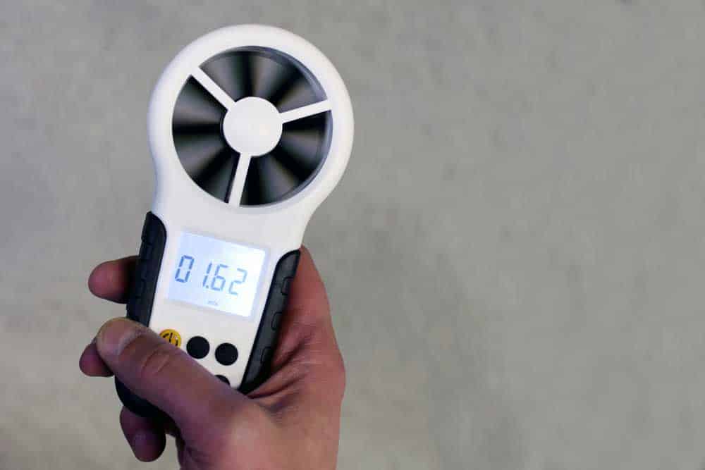 A handheld anemometer indicating wind speeds on its LCD